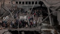 Tak hanya menaiki kereta, sejumlah warga juga berjalan kaki meninggalkan kota Irpin, yang berada di wilayah Kyiv untuk mengungsi. Mereka tampak melintasi jembatan yang hancur ketika mencoba meninggalkan kota Irpin, Sabtu (5/3/2022) waktu setempat. Jedrzej Nowicki/Agencja Wyborcza.pl via REUTERS.