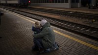 Seorang warga dengan putranya melihat kereta yang berangkat saat mereka mencoba melarikan diri di stasiun Kyiv, Ukraina, Kamis (3/3/2022). AP Photo/Emilio Morenatti.