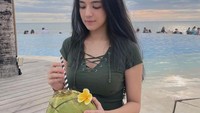 Minum kelapa di tepi pantai juga dilakukan DJ Una untuk menenangkan diri. Membiarkan rambutnya terurai, DJ Una tampak cantik alami. Foto: Instagram/putriuna