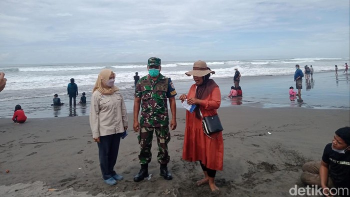 Petugas menegur wisatawan di Pantai Parangtritis yang tidak mengenakan masker, Minggu (6/3/2022).