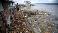 Seorang bapak bersama anaknya memerhatikan tumpukan sampah kiriman di bibir pantai Teluk Palu, Sulawesi Tengah, Sabtu (5/3/2022).