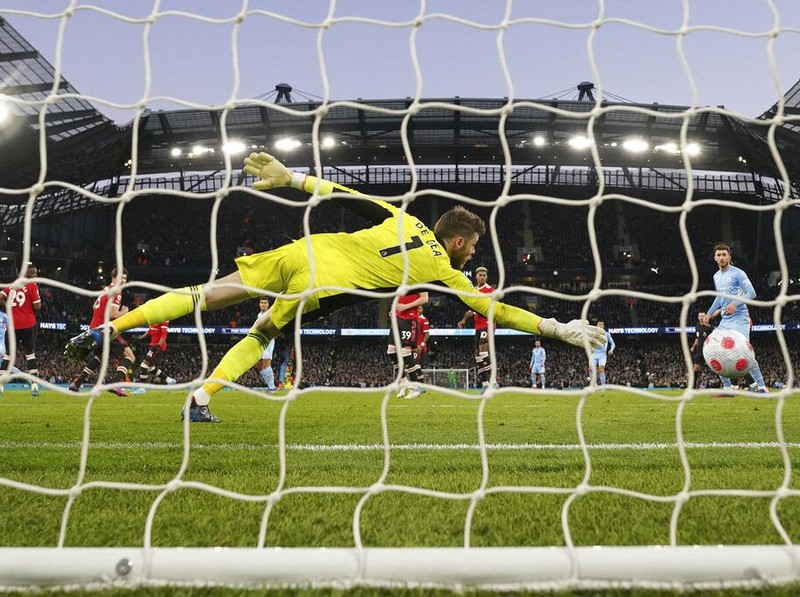 Manchester United's goalkeeper David de Gea, center, fails to save the ball as Manchester City's Riyad Mahrez, left, scores his side's third goal during the English Premier League soccer match between Manchester City and Manchester United, at the Etihad stadium in Manchester, England, Sunday, March 6, 2022. (AP Photo/Jon Super)