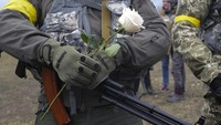 Seorang anggota Pasukan Pertahanan Teritorial Ukraina memegang bunga selama upacara pernikahan untuk anggota Pasukan Pertahanan Teritorial Ukraina Lesia Ivashchenko dan Valerii Fylymonov selama perang Rusia-Ukraina di sebuah pos pemeriksaan di Kyiv, Ukraina, Minggu, 6 Maret 2022.