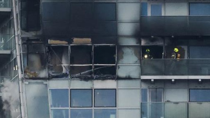 Firefighters extinguish the rest of a fire that broke out in the Relay Building, in Aldgate, east London, on March 7, 2022. - More than 125 firefighters battled a blaze at a tower block housing apartments and offices near the City of London, as burning debris fell to the ground. Police evacuated the high-rise building, after the fire erupted on its 17th floor and sent thick smoke into the sky. London mayor said 20 fire trucks and more than 125 firefighters were trying to douse the flames in the Aldgate district. (Photo by Tolga Akmen / AFP)