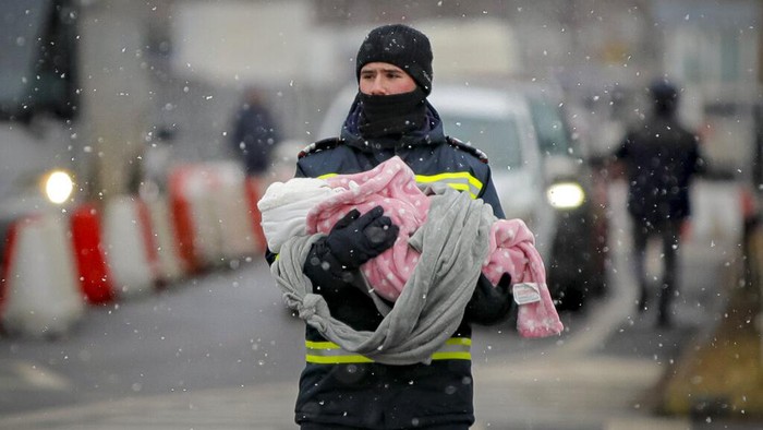 Cuaca Dingin Menambah Derita Korban Perang Ukraina A firefighter holds the baby of a refugee fleeing the conflict from neighboring Ukraine at the Romanian-Ukrainian border, in Siret, Romania, Monday, March 7, 2022. (AP Photo/Andreea Alexandru)