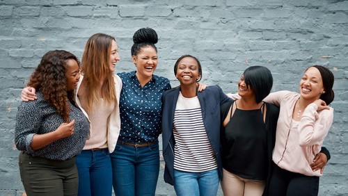 Portrait of a diverse group of young women standing together against a gray wall outside