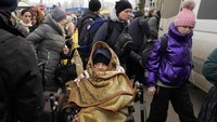 Pengungsi lansia menggunakan kursi roda menggigil kedinginan di perbatasan Ukraina-Moldova, Minggu (7/3/2022).  (AP Photo/Sergei Grits)