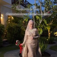 Dengan gaun bentuk duyung yang memperlihatkan lekuk tubuhnya, Venna Melinda tampil begitu menawan. Penampilannya itu dilengkapi dengan hijab berwarna senada dan sebuah hand bouquet berpita merah yang digenggamnya. Foto: Instagram