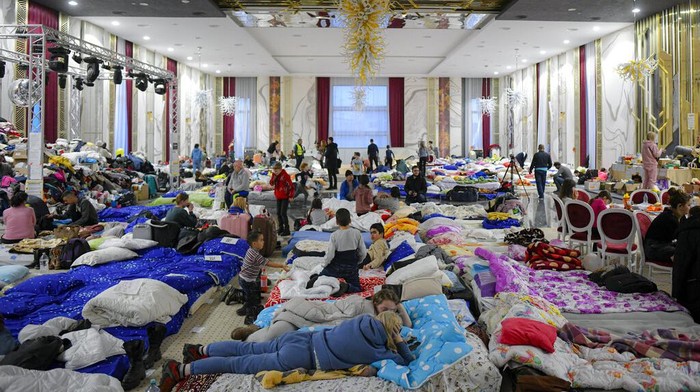 Refugees who fled the Russian invasion from neighbouring Ukraine sit inside a ballroom converted into a makeshift refugee shelter at a 4-star hotel & spa, in Suceava, Romania, Friday, March 4, 2022. At 4-star hotel & spa some 50 km from the border with Ukraine, wedding parties and conferences have been canceled and the ballroom converted into a makeshift refugee shelter where those who have escaped the Russian invasion come to rest and warm up before continuing their journey. (AP Photo/Andreea Alexandru)