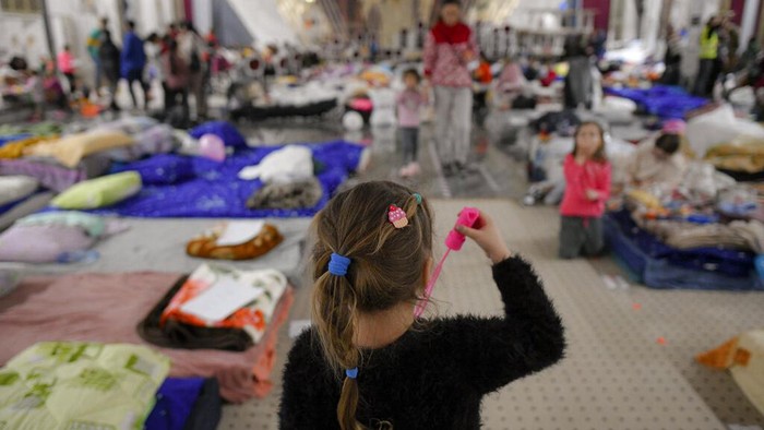 Refugees who fled the Russian invasion from neighbouring Ukraine sit inside a ballroom converted into a makeshift refugee shelter at a 4-star hotel & spa, in Suceava, Romania, Friday, March 4, 2022. At 4-star hotel & spa some 50 km from the border with Ukraine, wedding parties and conferences have been canceled and the ballroom converted into a makeshift refugee shelter where those who have escaped the Russian invasion come to rest and warm up before continuing their journey. (AP Photo/Andreea Alexandru)