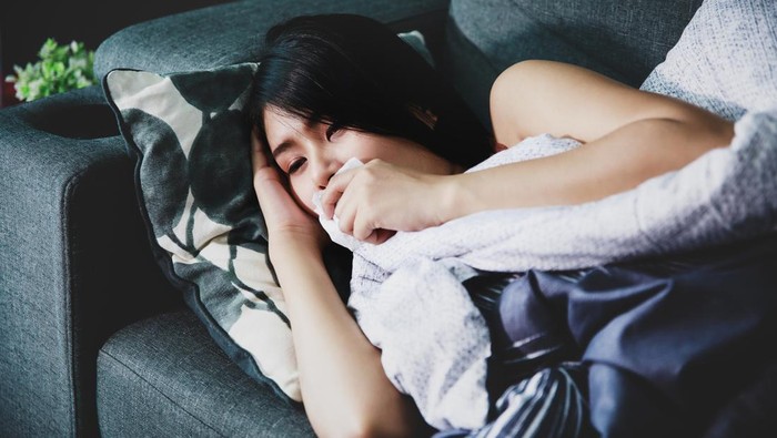 sakit tenggorokan Close up asian woman covered with a blanket lying in bed with high fever and a flu