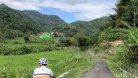 Pesepeda beristirahat menikmati perbukitan dan lembah subur di Desa Cibodas, Kutawaringin, Bandung.