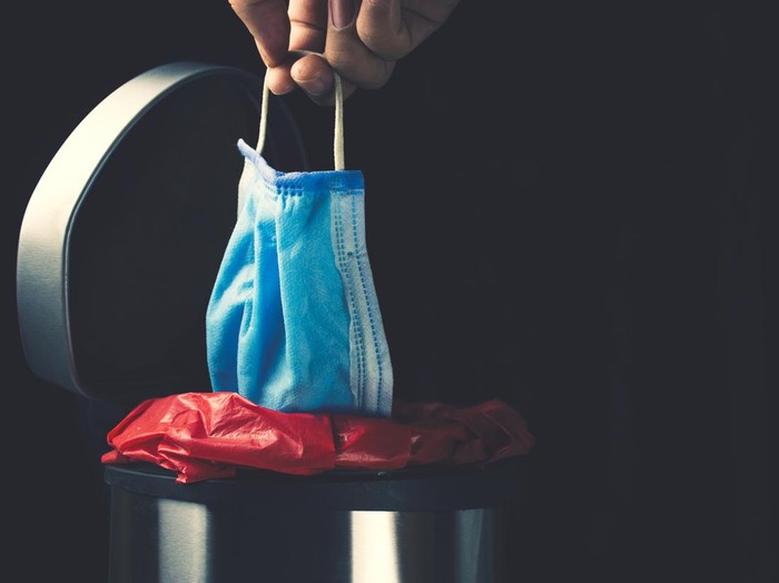masker Hand leave disposable medical mask into infected trash bin
