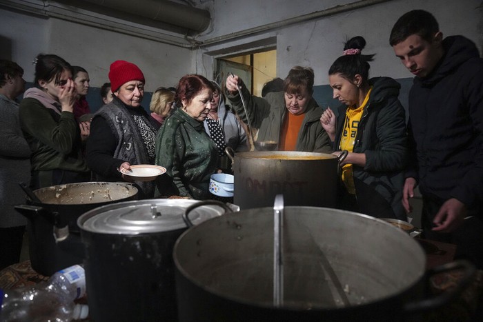 Ukrainian servicemen, right, distributes water to people in Mariupol, Ukraine, Sunday, March 6, 2022. (AP Photo/Evgeniy Maloletka)