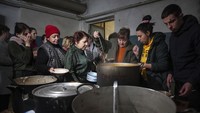 Pengungsi mengantre pembagian makanan di penampungan pengungsi bawah tanah di Mariupol, 7 Maret 2022. Badan anak-anak PBB (UNICEF) percaya bahwa ratusan ribu dari mereka yang mengungsi adalah anak-anak. Pihak berwenang dan PBB memperkirakan jumlah pengungsi akan terus meningkat saat tentara Rusia bergerak lebih dalam Ukraina, terutama saat mendekati Kyiv.
