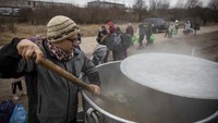 Relawan kemanusiaan, Lukas Saranga memasak makanan menggunakan panci raksasa di perbatasan Polandia, 8 Maret 2022.  UNHCR mengatakan pada Senin, sebanyak 1.204.403 pengungsi berada di Polandia. Jumlahnya membengkak 176.800 dalam 24 jam terakhir. (AP Photo/Visar Kryeziu)