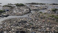 Tampak warga melintas di tepi Sungai Tawi yang penuh sampah.