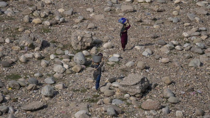 A man collects sand on horse backs and moves past the polluted banks of River Tawi in Jammu, India, Wednesday, March 9, 2022.(AP Photo/Channi Anand)