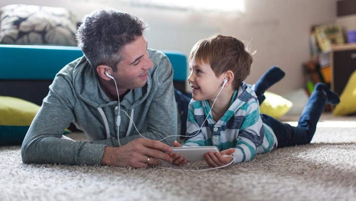 Smiling boy listenig music with his father