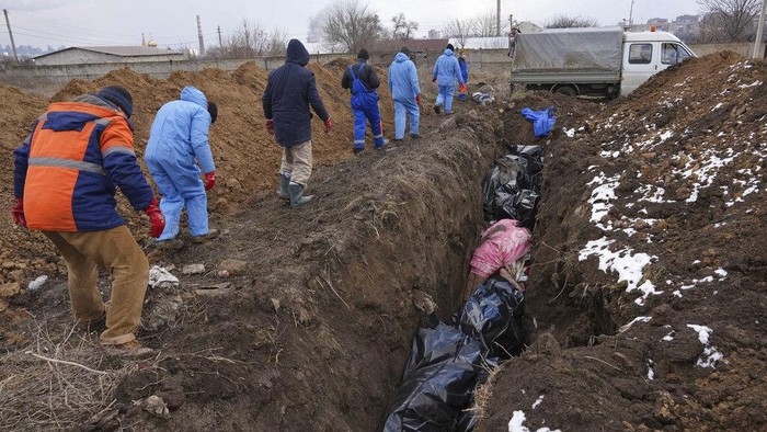 Dead bodies are put into a mass grave on the outskirts of Mariupol, Ukraine, Wednesday, March 9, 2022 as people cannot bury their dead because of the heavy shelling by Russian forces. (AP Photo/Evgeniy Maloletka)
