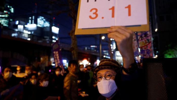 11 Tahun Tsunami Jepang, Aktivis Anti-nuklir Turun ke Jalan A protester wearing a protective suit makes his way during an anti-nuclear rally in front of the headquarters of Tokyo Electric Power Co (TEPCO), the operator of the tsunami-crippled Fukushima Daiichi nuclear plant, on the day marking the 11th anniversary of the disaster in Tokyo, Japan March 11, 2022. REUTERS/Kim Kyung-Hoon