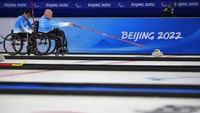 Dave Samsa dari Amerika Serikat mendorong satu ton saat rekan setimnya Batoyun Uranchimeg membantu selama kompetisi curling kursi roda mereka melawan Swedia di Paralimpiade Musim Dingin 2022, Kamis, (10/3/2022), di Beijing. AP/Dita Alangkara
