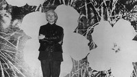 Andy Warhol yang juga sutradara film berdiri di depan salah satu lukisan sutra bunganya yang berskala raksasa.  Foto: Getty Images/John Minihan