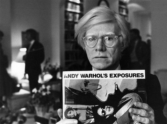 Andy Warhol (1926 - 1987), American pop artist and filmmaker, holding an example of one of his posters.  Original Publication: People Disc - HM0195   (Photo by John Minihan/Getty Images)