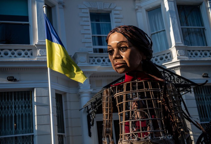 Boneka Raksasa Little Amal LONDON, ENGLAND - MARCH 10: The Little Amal puppet lays flowers outside the Ukrainian Embassy on March 10, 2022 in London, England. Little Amal is a 3.5 metre tall puppet representing refugee children. Last year she walked 8000 miles around Europe to raise awareness of their plight. (Photo by Chris J Ratcliffe/Getty Images)