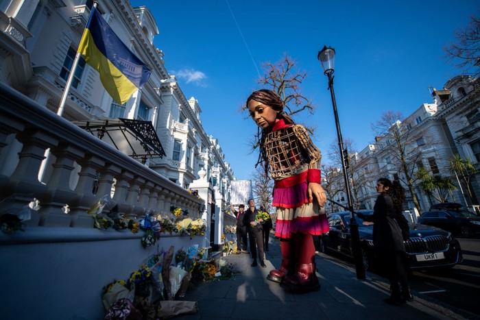 Boneka Raksasa Little Amal LONDON, ENGLAND - MARCH 10: The Little Amal puppet lays flowers outside the Ukrainian Embassy on March 10, 2022 in London, England. Little Amal is a 3.5 metre tall puppet representing refugee children. Last year she walked 8000 miles around Europe to raise awareness of their plight. (Photo by Chris J Ratcliffe/Getty Images)