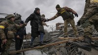 Prajurit Ukraina membantu seorang wanita yang membawa seekor anjing kecil melintasi Sungai Irpin di jalur improvisasi sambil membantu orang-orang yang melarikan diri dari kota Irpin, Ukraina. (AP/Vadim Ghirda)