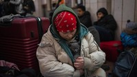 Seorang gadis Ukraina memeluk kucingnya dengan mantelnya di dalam stasiun kereta api Lviv. (AP/Bernat Armangue)