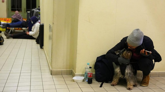 Hewan-hewan Peliharaan Ikut Ngungsi Gara-gara Perang Rusia-Ukraina A woman from neighboring Ukraine, sits with her dog at a train station that was turned into an accommodation center in Przemysl, Poland, on Thursday, Feb. 24, 2022. (AP Photo/Petr David Josek)
