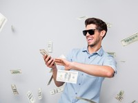 Photo of cheerful excited ecstatic overjoyed man throwing money away, showing his wealthiness wearing denim isolated over grey color background