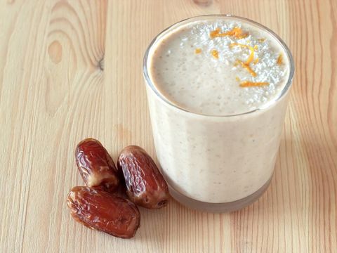 Healthy organic date and apple milk smoothie powdered shredded coconut and orange zest. Fresh diet breakfast. Wooden background. Selective focus.
