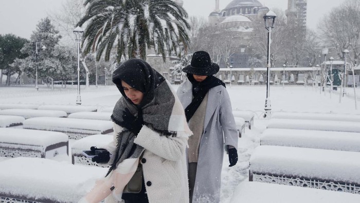 People, with the Sultanahmet Mosque, known as the Blue Mosque in the background, walk during a snow storm in Istanbul, Turkey March 11, 2022. REUTERS/Dilara Senkaya