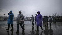 Pejalan kaki berjalan di bawah hujan salju tipis di sebelah Bosphorus di Istanbul, Turki, Kamis 10 Maret 2022. AP Photo/Emrah Gurel.