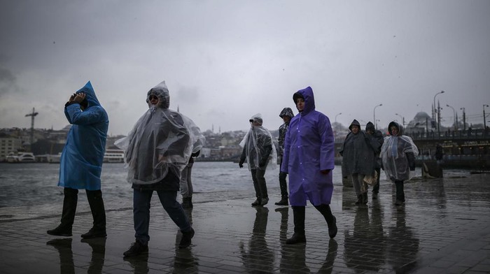 Pedestrians walk under light snowfall next to the Bosphorus in Istanbul, Turkey, Thursday, March 10, 2022. (AP Photo/Emrah Gurel)