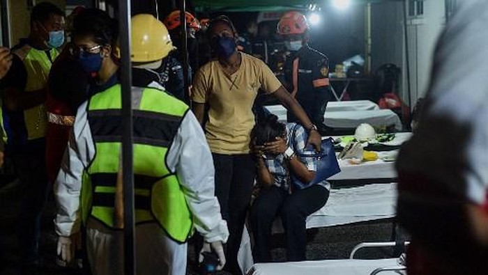 Rescue workers carry out the body of a victim after a landslide was triggered by heavy rains in the township of Ampang, outside Kuala Lumpur early on March 11, 2022. (Photo by Arif Kartono / AFP)