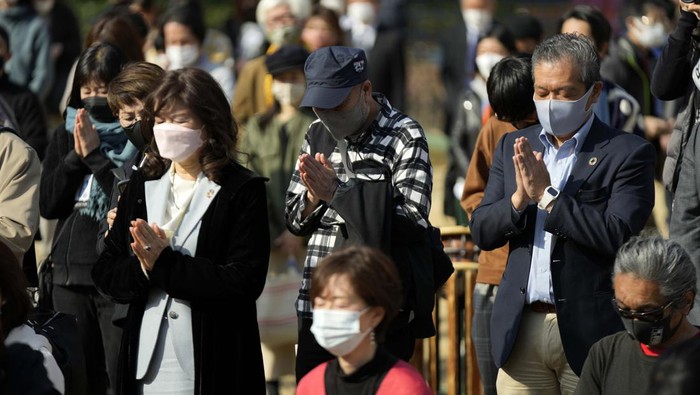 A visitor prays at a makeshift altar to mourn for the victims of the March 11, 2011 earthquake and tsunami during a special memorial event Friday, March 11, 2022, in Tokyo. Japan on Friday marked the 11th anniversary of the massive earthquake, tsunami and nuclear disaster that struck Japan's northeastern coast. (AP Photo/Eugene Hoshiko)