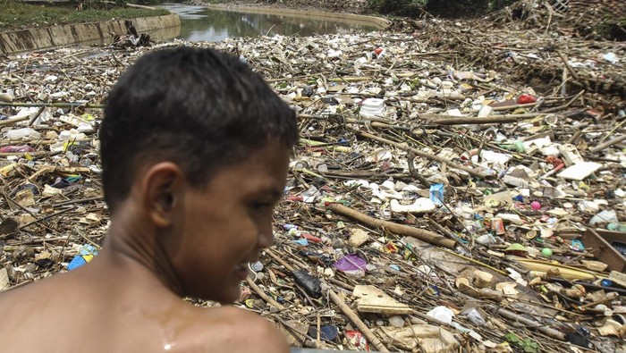 Warga melihat sampah yang terbawa aliran air dan menyangkut di salah satu jembatan di Kali Pesanggrahan, Cipayung, Depok, Jawa Barat, Jumat (11/3/2022). Sampah menyangkut tersebut membuat aliran air kali terhambat dan menyebabkan banjir di kawasan itu. ANTARA FOTO/Asprilla Dwi Adha/wsj.