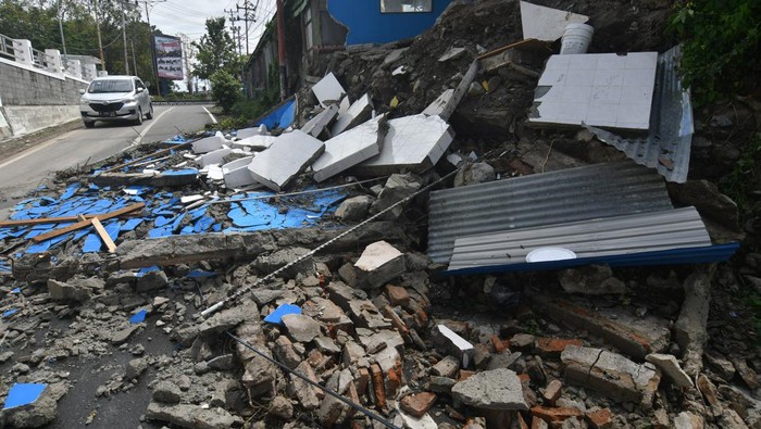 Pengendara melintasi puing pagar dan bangunan SMP Negeri 2 Palu yang ambruk akibat hujan di Palu, Sulawesi Tengah, Sabtu (12/3/2022). Tidak ada korban dalam peristiwa tersebut, namun arus lalu lintas sempat terhambat akibat puing bangunan yang roboh menutupi badan jalan. ANTARA FOTO/Mohamad Hamzah/rwa.