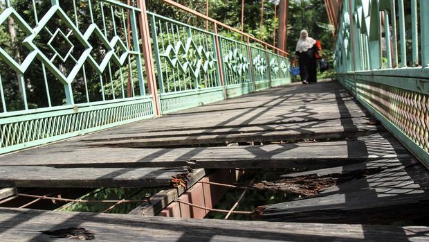 JEMBATAN PENGHUBUNG DEPOK JAKARTA BERLUBANG Warga berjalan melintasi jembatan yang berlubang di Jembatan Wiratman, Srengseng Sawah, Jakarta, Sabtu (12/3/2022). Jembatan yang menghubungkan Kelurahan Srengseng Sawah, Jakarta Selatan dengan Kelurahan Pasir Gunung Selatan, Depok tersebut mengalami kerusakan pada papan pijak yang mulai berlubang serta besi yang berkarat sehingga dapat membahayakan warga yang melintas. ANTARA FOTO/Asprilla Dwi Adha/rwa.
