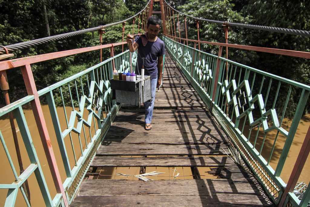 JEMBATAN PENGHUBUNG DEPOK JAKARTA BERLUBANG Warga berjalan melintasi jembatan yang berlubang di Jembatan Wiratman, Srengseng Sawah, Jakarta, Sabtu (12/3/2022). Jembatan yang menghubungkan Kelurahan Srengseng Sawah, Jakarta Selatan dengan Kelurahan Pasir Gunung Selatan, Depok tersebut mengalami kerusakan pada papan pijak yang mulai berlubang serta besi yang berkarat sehingga dapat membahayakan warga yang melintas. ANTARA FOTO/Asprilla Dwi Adha/rwa.