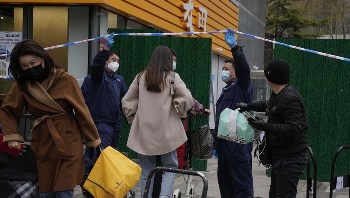 Workers control access into a closed off community on Sunday, March 13, 2022, in Beijing. The number of new coronavirus cases in an outbreak in China's northeast tripled Sunday and authorities tightened control on access to Shanghai in the east, suspending bus service to the city of 24 million and requiring a virus test for anyone who wants to enter. (AP Photo/Ng Han Guan)