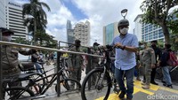 Dengan memakai kemeja biru dan celana jeans serta helm, ia terihat senang saat warga antusias menikmati JPO Pinisi Sudirman.