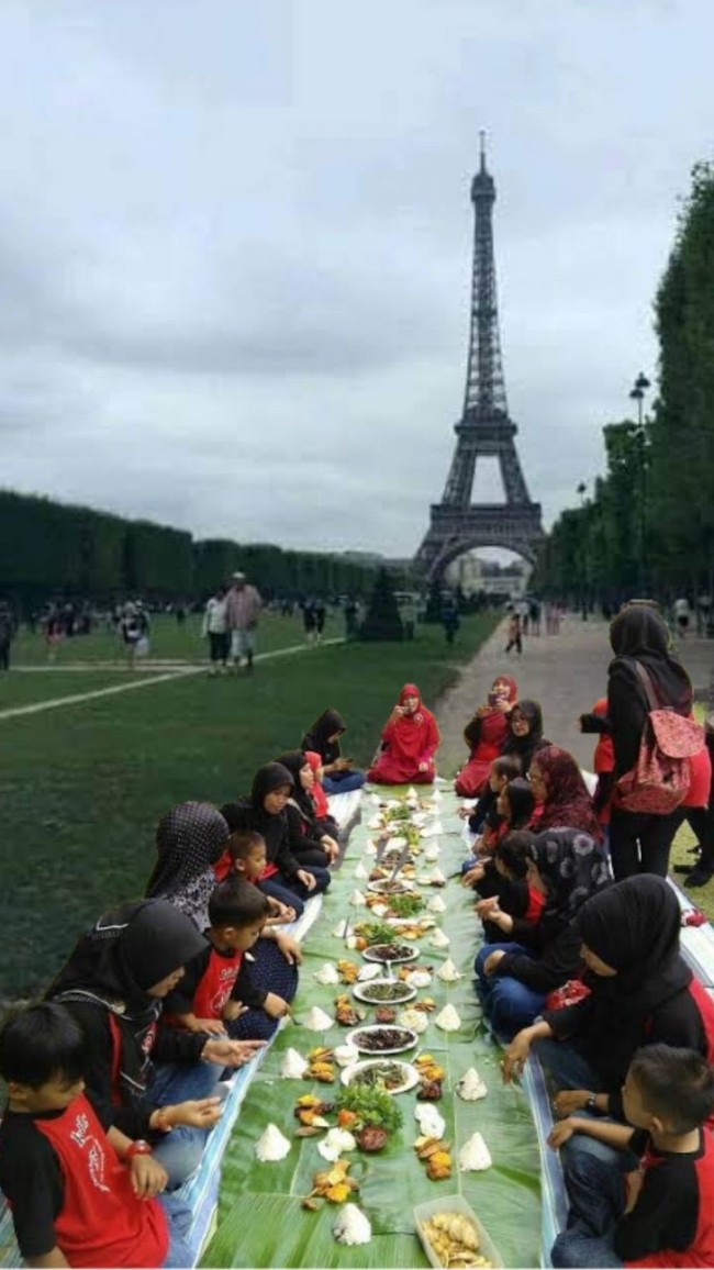 Momen saat emak-emak halu sedang liburan ke Paris. Nggak perlu keluar uang untuk makan mahal, cukup makan bekal sambil lesehan di depan menara Eiffel saja. Foto: Twitter/@djavelyne