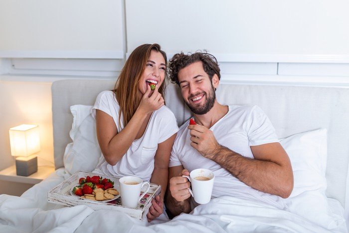 ilustrasi pasangan Young married couple in love eating breakfast in their bed. Good morning! Healthy breakfast in bed. Young beautiful love couple is having breakfast in bed.