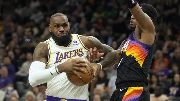 Los Angeles Lakers forward LeBron James, left, drives on Phoenix Suns forward Torrey Craig during the first half of an NBA basketball game, Sunday, March 13, 2022, in Phoenix. (AP Photo/Rick Scuteri)