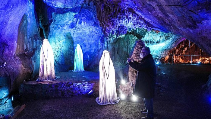 Melihat Gua Warna-warni di Jerman People visit the colorful, illuminated Dechen Cave in Iserlohn, Germany, Friday, March 11, 2022. The cave, which was discovered by two railway workers in 1868, is temporarily illuminated by light artist Wolfgang Flammersfeld. (AP Photo/Martin Meissner)